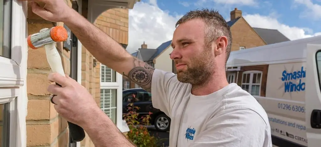 A Smashing Windows fitter sealing a new window frame, with the company van behind him